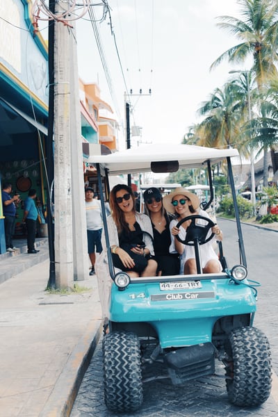 3 chicas en un carro de golf en la avenida principal de Isla Mujeres Mexico