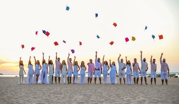 graduation in Cancun, people throwing their biretta in the air at the beach