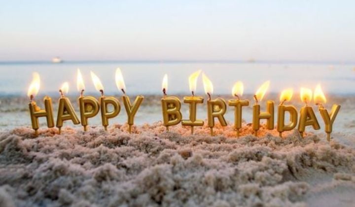 velas de cunpleaños en la arena formando la palabra "happy birthday"